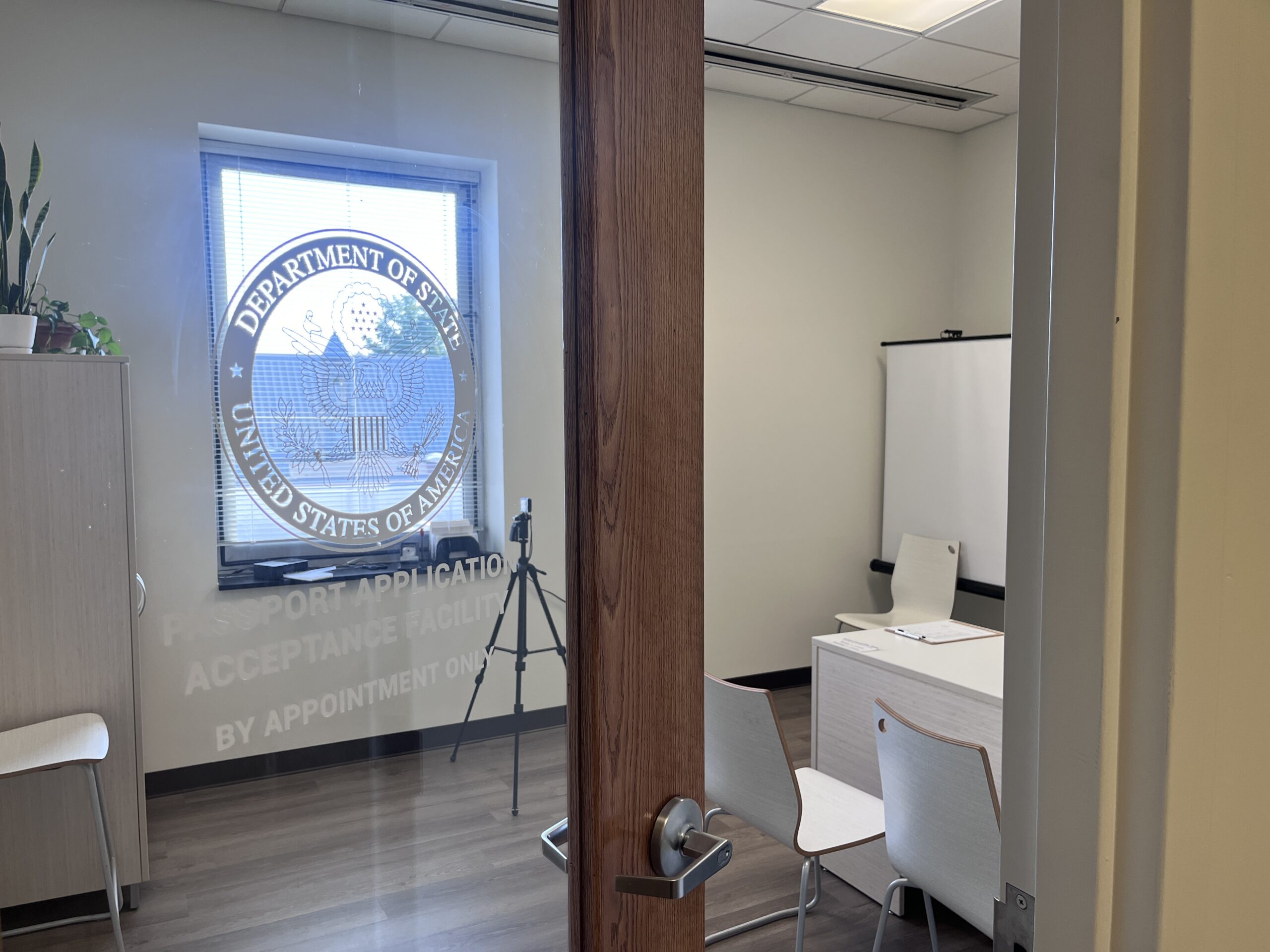 The Passport office door with desk, camera, and chair inside.