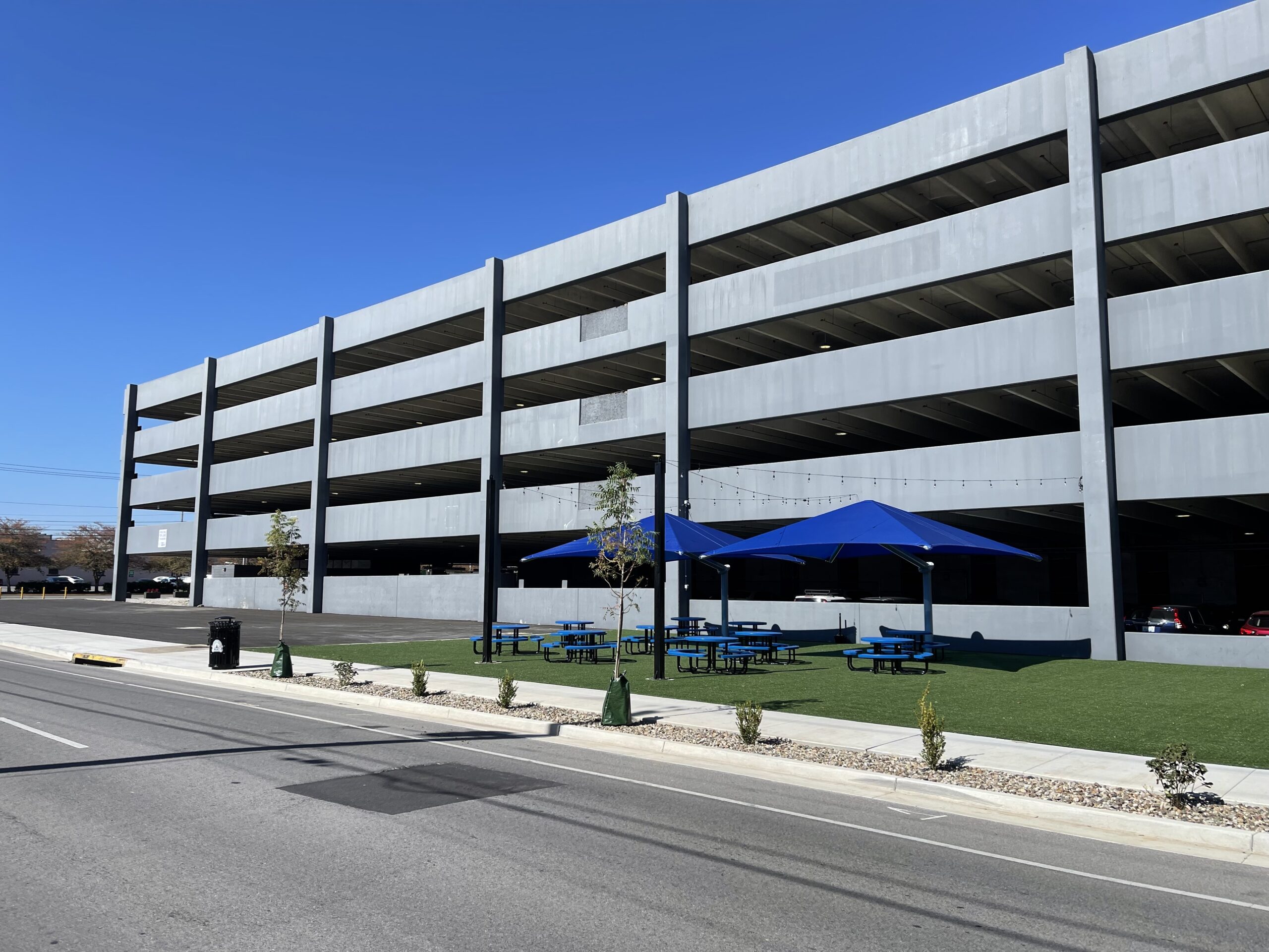 Photo of The Fringe Food Truck Park, a paved and astroturf picnic park situated in front of a four story parking garage