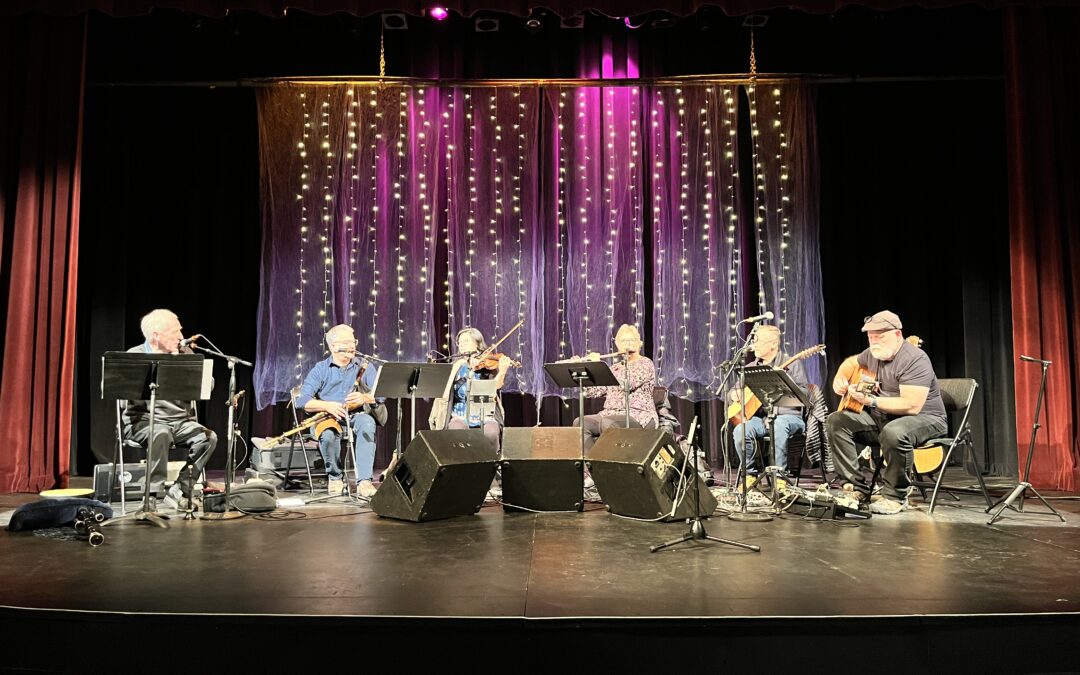 A band with 6 musicians playing on a stage.