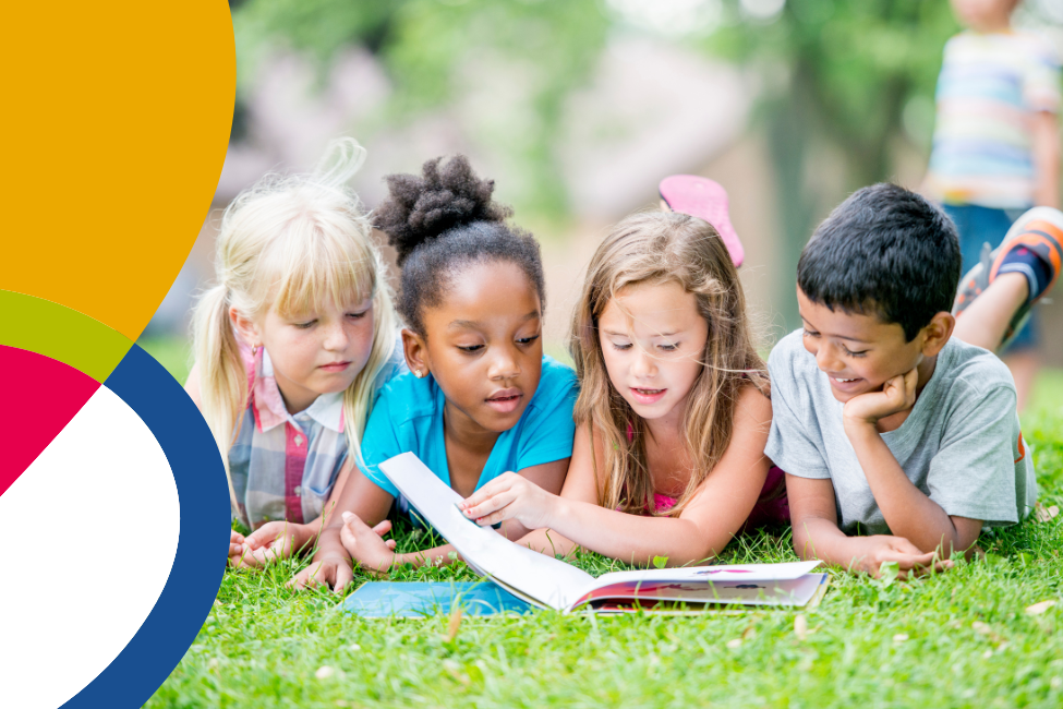 Children reading a book on the grass