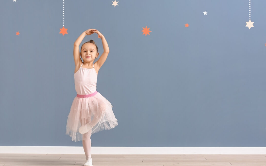 Girl in a pink tutu doing ballet in front of a blue wall