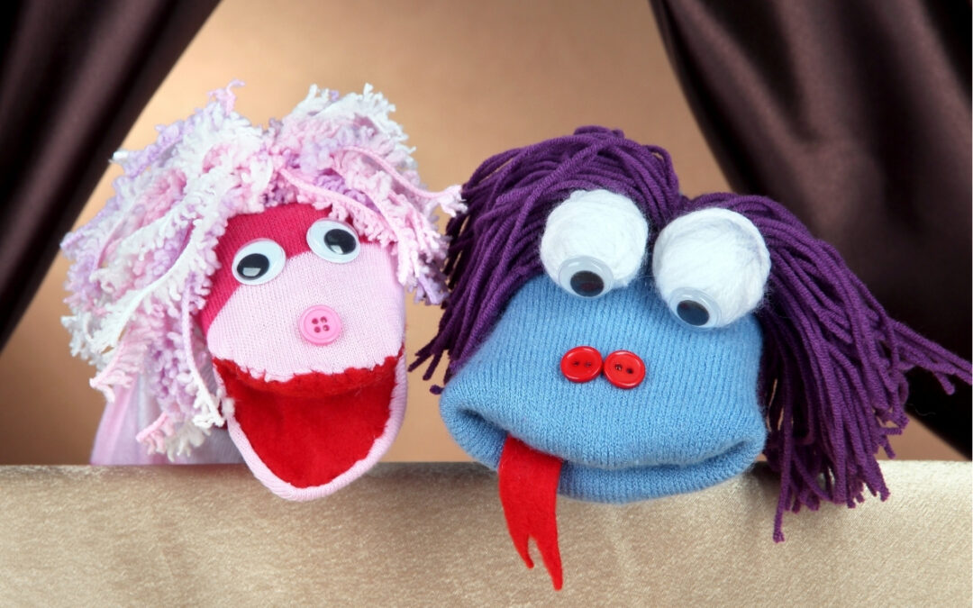Two colorful sock puppets in front of a curtain