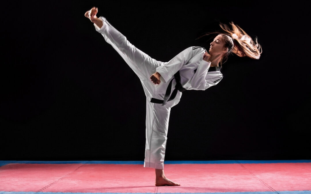 A young woman practices her high kick in a dark room