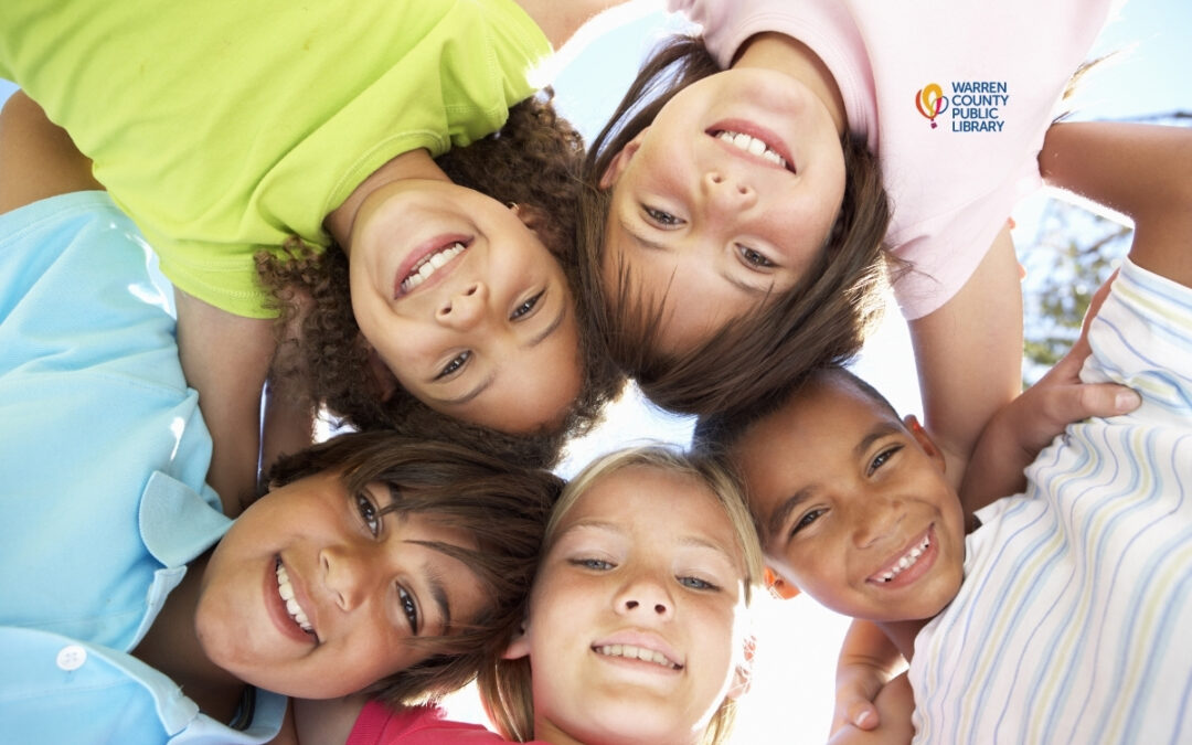 Group of kids huddled together smiling with Warren County Public Library logo