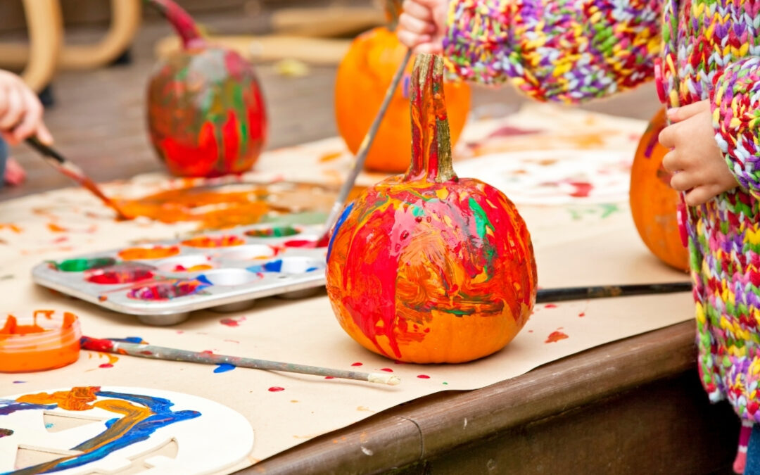 Pumpkins being painted a variety of colors on a table