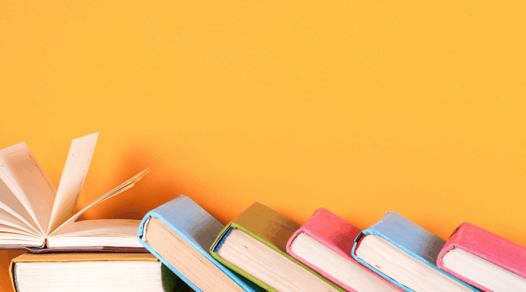 Leaning books against an orange backdrop.