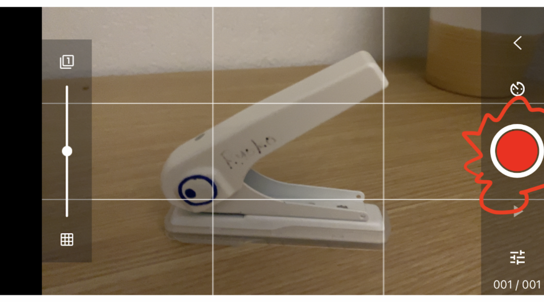 A white stapler with a drawn on eye through the lens of a phone camera