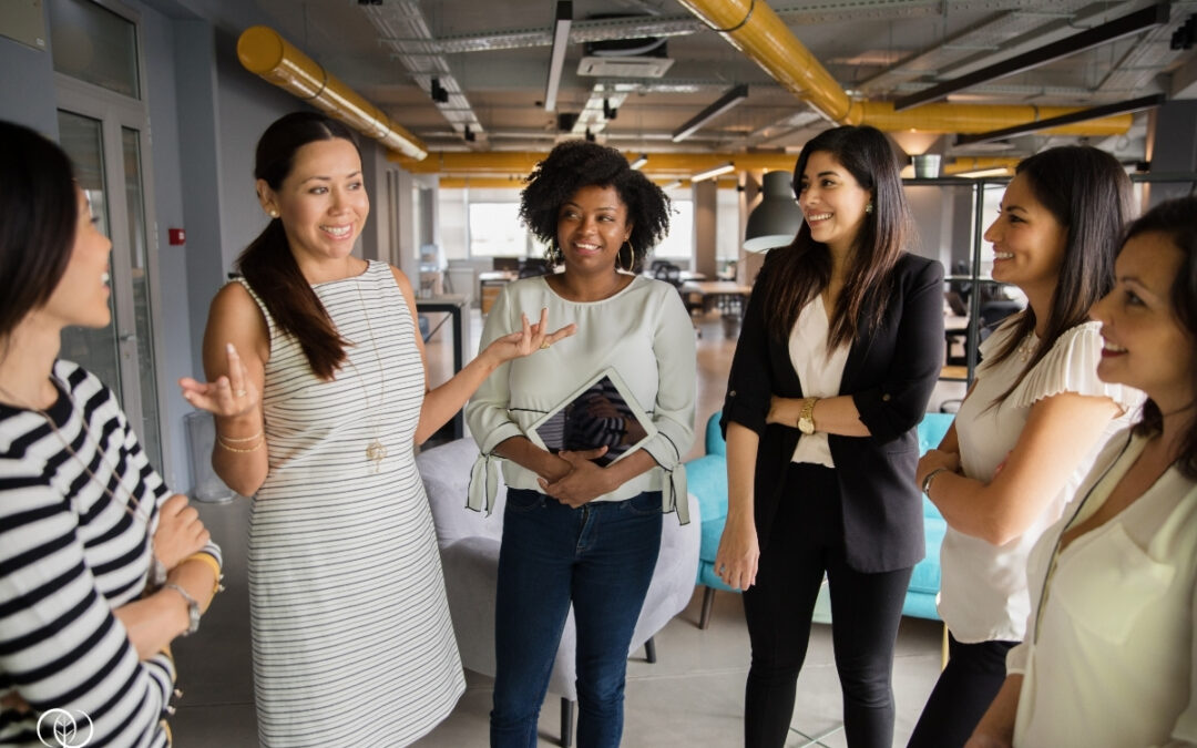 A group of women in business casual attire conversing