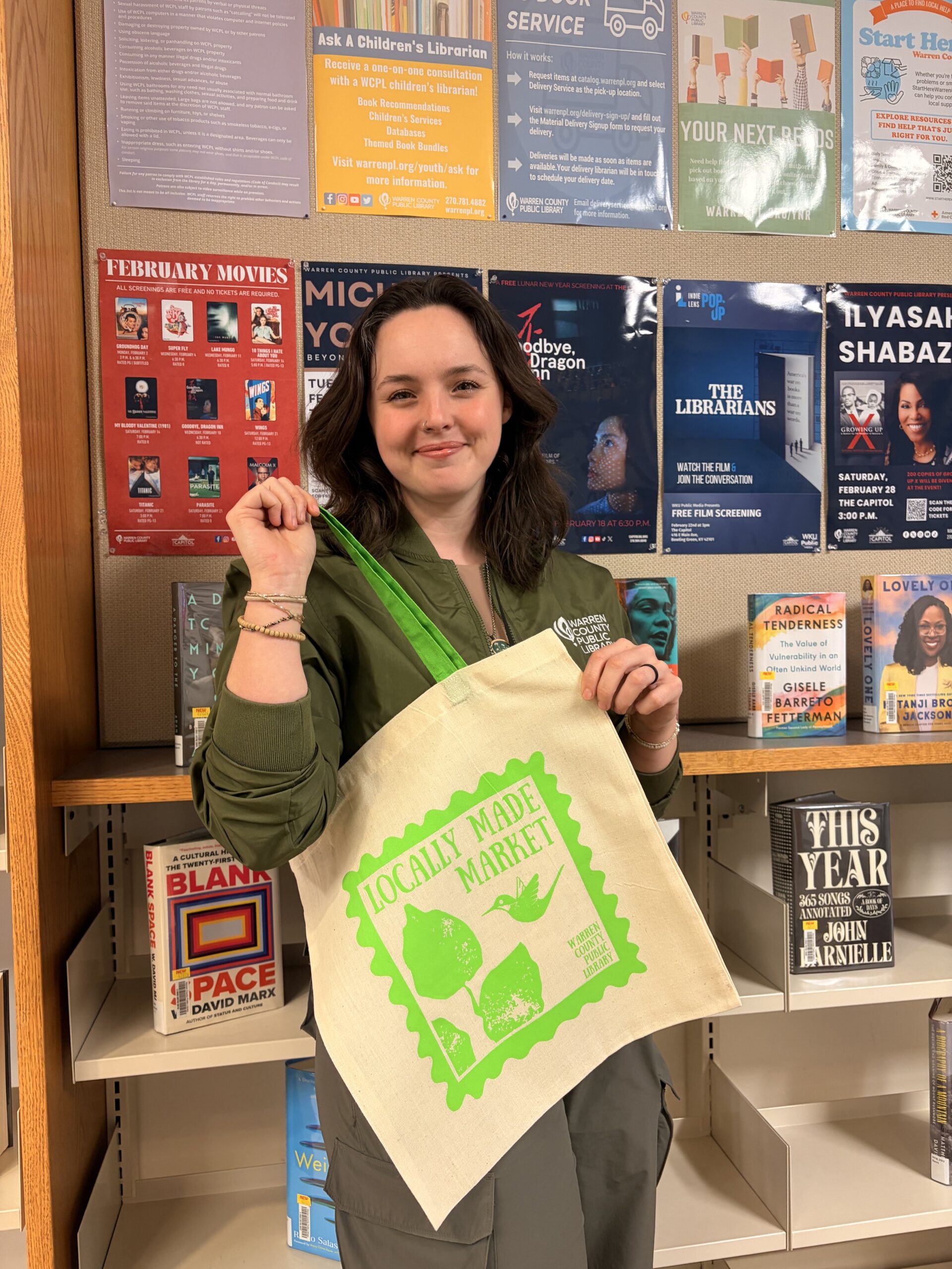 Woman holding a canvas bag with an image of a hummingbird advertising the Locally Made Market