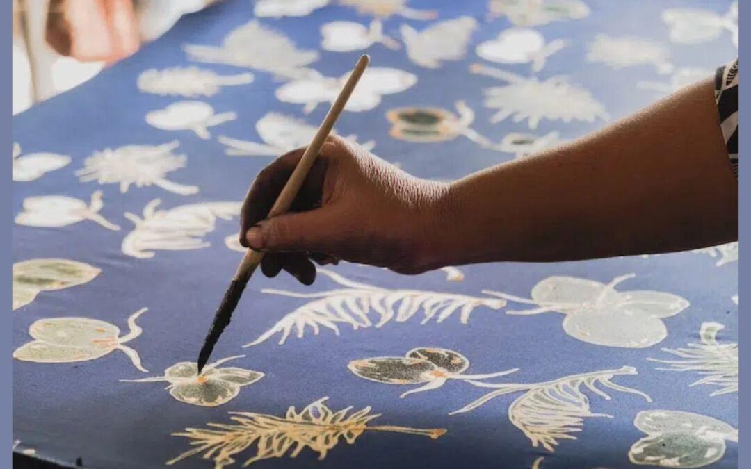 Hand painting feathers on a blue canvas.