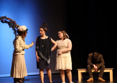 three female actresses talking in front of a despondent male on a bendch