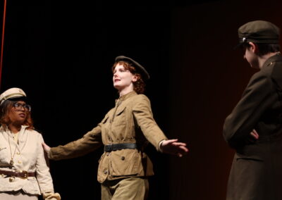 A uniformed actor making a speech between two others