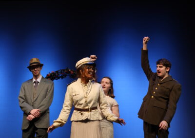 one actor raising a fist with others on stage