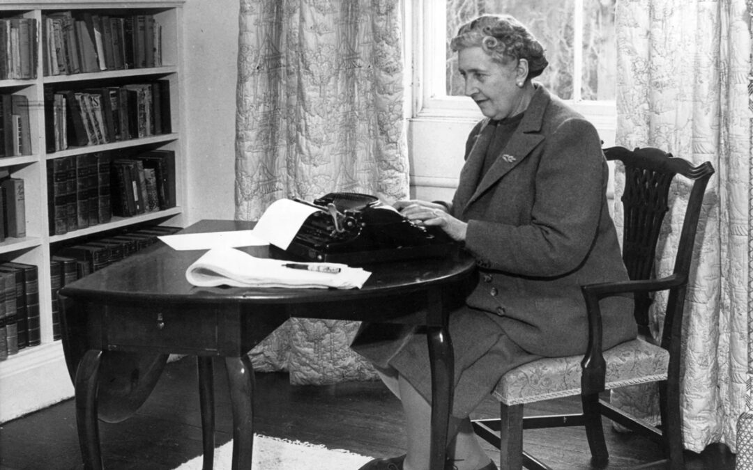 Black and white image of author Agatha Christie sitting at a typewriter